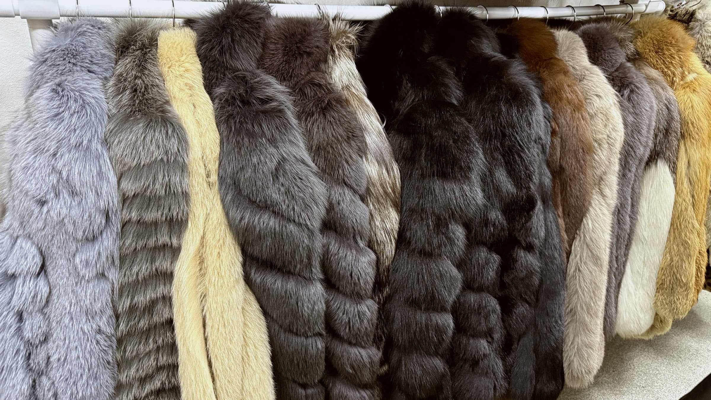 A rack of vintage fox coats at TOKONAME FUR HOUSE — silver, golden, cross, dark, and red varieties